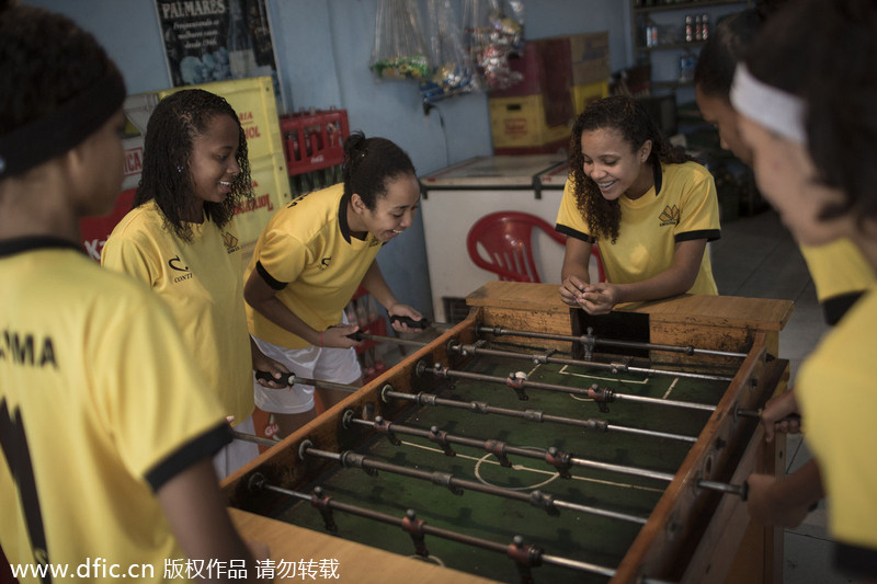 Des jeunes filles jouent au baby-foot, dans le bidonville de Borel à Rio de Janeiro, au Brésil, le 10 mai 2014. La journée d’ouverture de la Coupe du Monde approchant, les gens continuent à organiser des manifestations. Mais le football est toujours une force unificatrice. [Photo/IC]