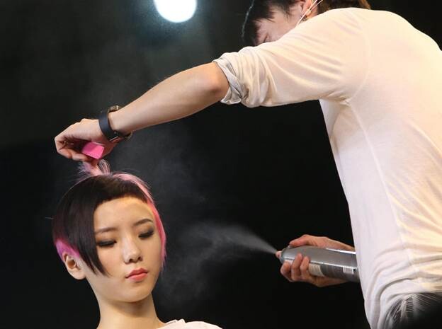 Un coiffeur travaille sur la chevelure d'un mannequin lors de la 9e édition du Festival Asiatique de Coiffure, mercredi à Shanghai. Le festival, qui a débuté mercredi et se termine vendredi, propose une série d'événements, comme un concours de coiffure et des sessions de formation. [Photo Gao Erqiang / Asianewsphoto]