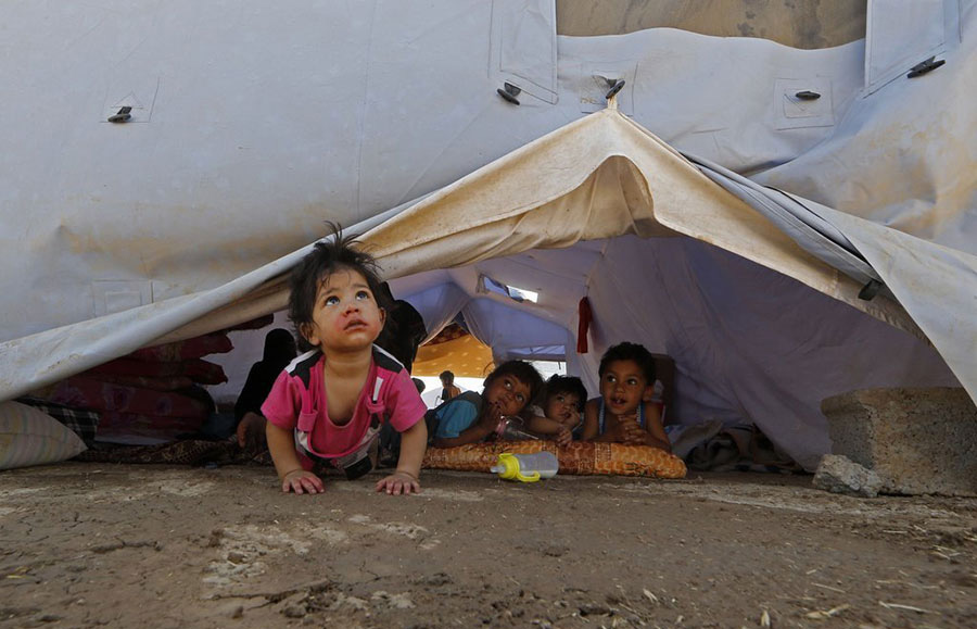 De jeunes Irakiens déplacés se retrouvent à l'intérieur d'une tente du HCR dans un camp provisoire mis en place pour abriter les personnes qui fuient la violence dans le nord de l'Irak, le 17 Juin 2014 à Askikalak, à 40 kilomètres à l'ouest de la capitale de la région autonome kurde d'Erbil. Des militants ont poussé une offensive de près d’une semaine pour envahir plusieurs parties de l'Irak à moins de 60 kilomètres (37 miles) de Bagdad, l'ONU ayant annoncé l’existence d’une sérieuse menace pour le pays. 