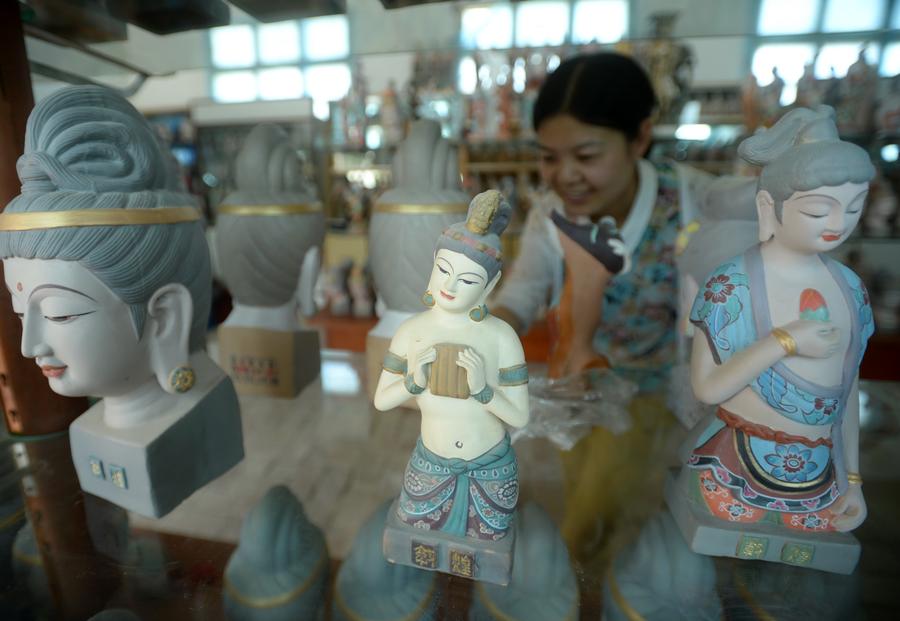 Une visiteuse admire des sculptures peintes à l’Institut de Formation des Statues Peintes de Dunhuang, le 26 juin 2014. 