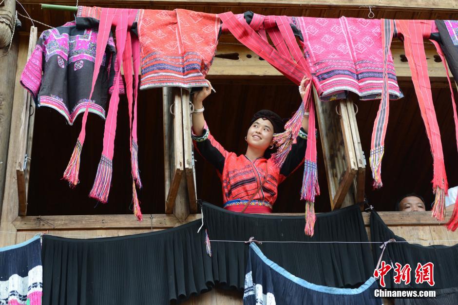 Une jeune fille de l'ethnie Yao aère sa veste rouge et sa belle robe préservées dans une boite