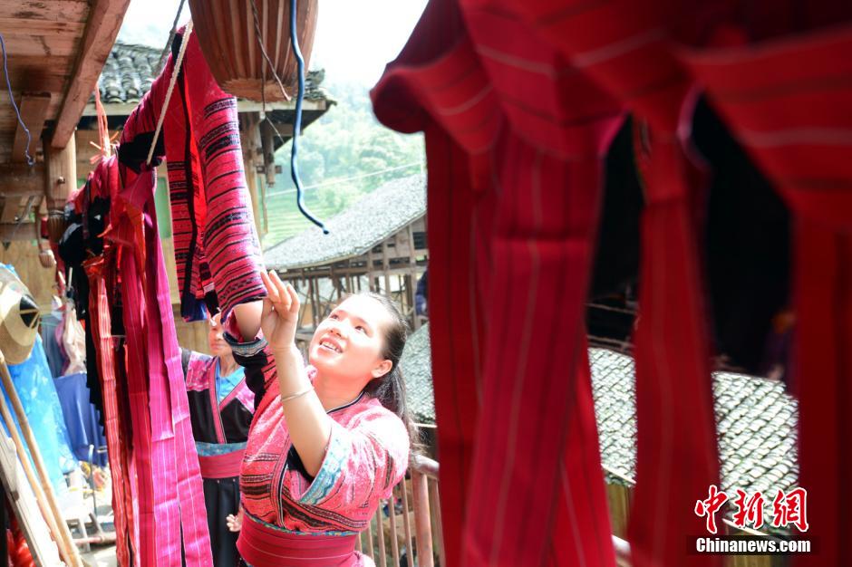 Une jeune de l'ethnie Yao aère sa veste rouge et sa belle robe préservées préserve dans une boîte