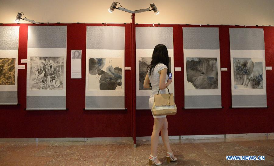 Une femme regarde une peinture chinoise traditionnelle lors d'une exposition de la calligraphie et de la peinture traditionnelle chinoises à Tirana, capitale de l'Albanie, le 25 juillet 2014.