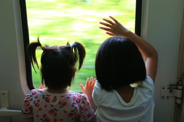 Les deux sœurs regardent à travers une fenêtre de leur train en direction de Shunde, où leurs parents travaillent, le 10 juillet 2014.
