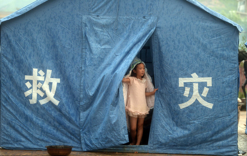 Une fillette se met à l’abri de la pluie dans une tente provisoire du village de Longtoushan à Ludian, dans la province du Yunnan, le jeudi 7 août 2014.
