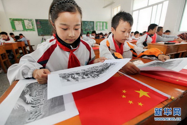 Le 17 septembre à Lianyungang (Province du Jiangsu), les élèves de l'école primaire du District de Ganyu, rue Huanghai, regardent des photos historiques concernant la Guerre de Résistance contre le Japon. 
