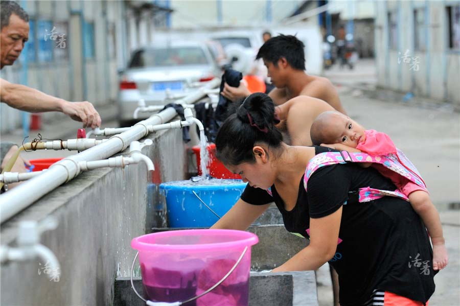 Ran Yeqin, enceinte de 8 mois, porte sa fille d'un an et demie sur son dos alors qu'elle est occupée à faire la lessive. Elle prépare aussi le repas pour son mari et prend soin de son enfant. [Photo/qq.com]