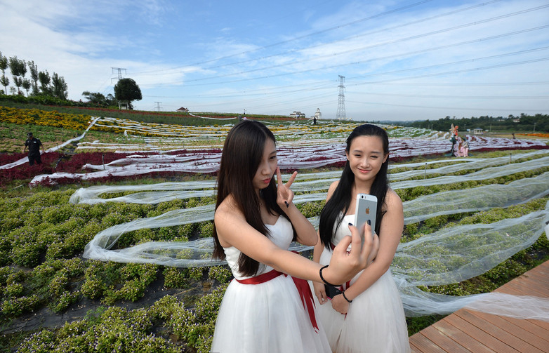 Des mannuquns portant la robe de mariage de 4 100 mètres de long dans la « vallée de Ziyixiangxun » à Chengdu, dans la province du Sichuan, le mercredi 24 septembre 2014.