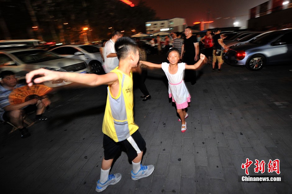 Sur le parking du gymnase de Wukesong, avenue Chang'an Ouest, deux enfants dansent au son d'un rythme puissant. Photo Jin Shuo pour Xinhua. 