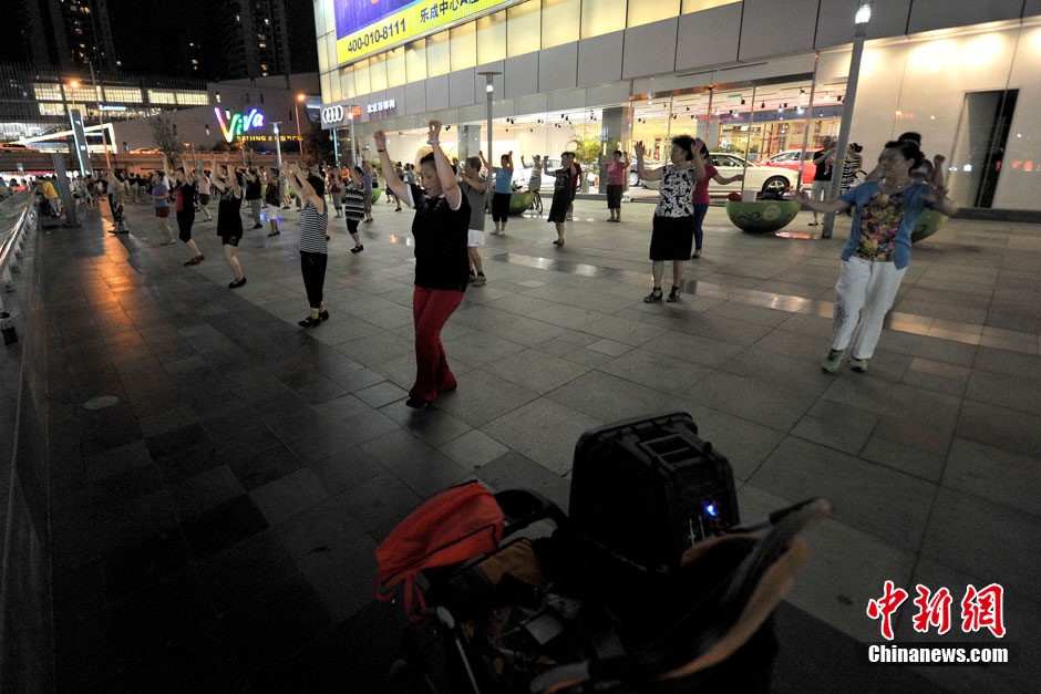 La danse de square « Centre de l'univers » devant le centre commercial Joy City de Shuangjing. Ici se réunissent tous les soirs à 19h trois générations de danseurs qui arrivent petit à petit, formant toutes sortes de petits groupes séparés de danse de square, qui ont tôt fait de remplir cet endroit. Photo Jin Shuo pour Xinhua. 