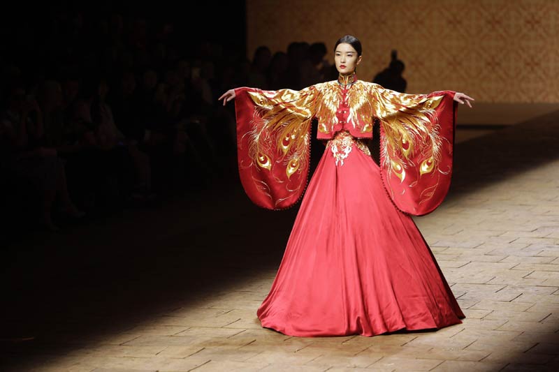 Un modèle, lors de la Collection de haute couture NE TIGER 2014, une création du designer chinois Zhang Zhifeng, devant une image de l’Empereur Jaune Xuan Yuan, considéré par beaucoup comme l'ancêtre du peuple chinois, à l’occasion de la China Fashion Week à Beijing, le 25 octobre 2014.