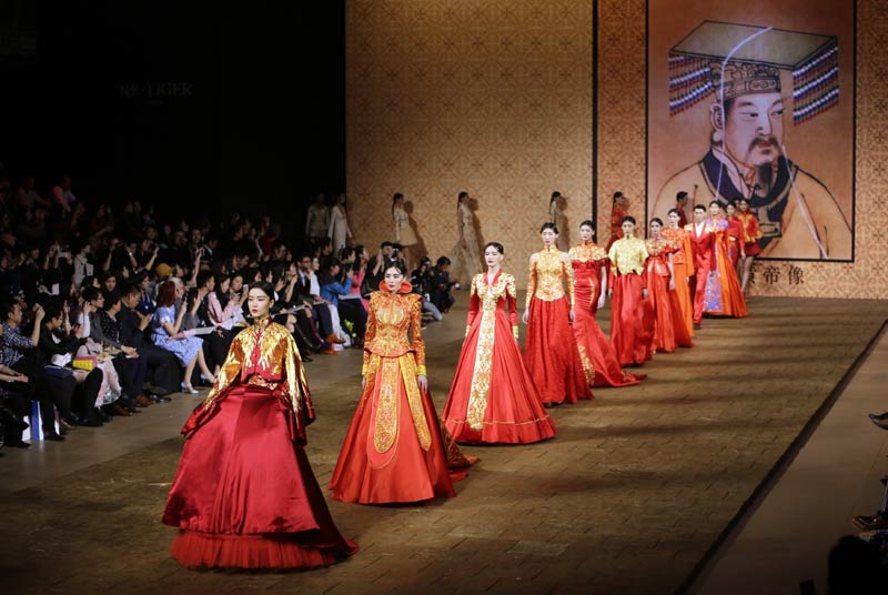 Les modèles de créations actuelles par le designer chinois Zhang Zhifeng, lors de la Collection haute couture NE TIGER 2014, devant une image de l’Empereur Jaune Xuan Yuan, considéré par beaucoup comme l'ancêtre du peuple chinois, à l’occasion de la China Fashion Week à Beijing, le 25 octobre 2014. 