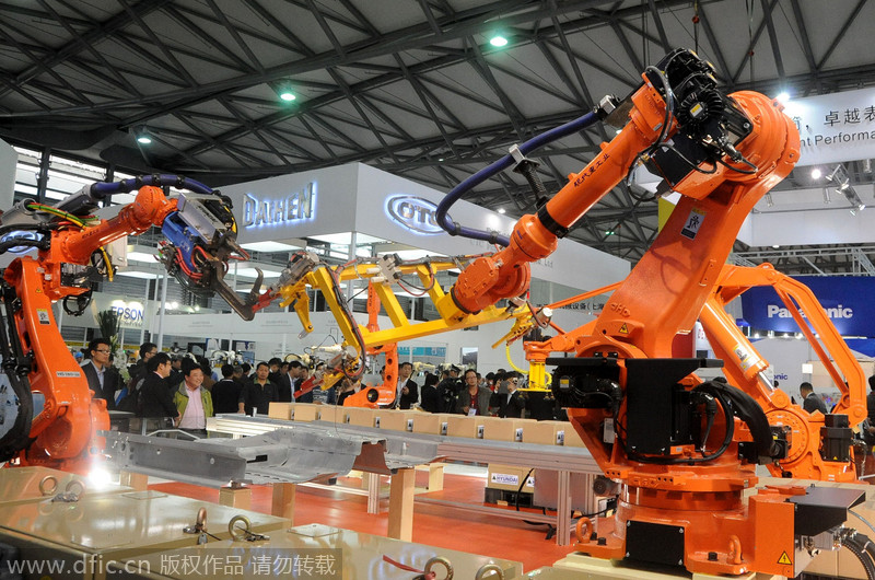 Deux robots de chaîne de montage font une démonstration le transfert d'objet pendant le 16e Salon international de l'industrie de Chine à Shanghai, le 4 novembre 2014. 