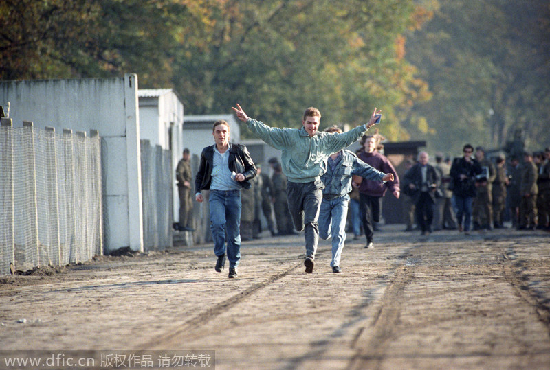 Des jeunes hommes traversent joyeusement un poste-frontière à Berlin, en Allemagne, le 10 novembre 1989.
