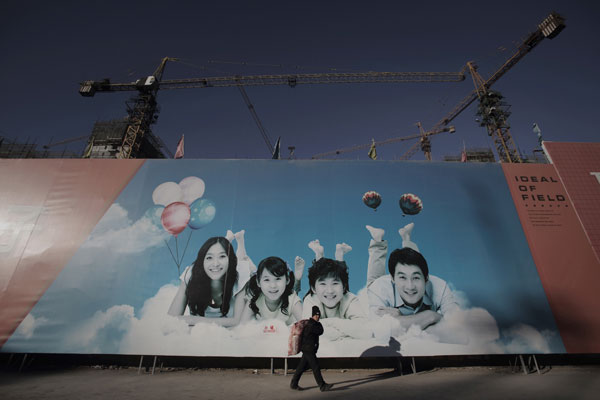 Un ouvrier passe devant un immense panneau d'affichage, servant de mur au site d'un chantier de construction, à Yanjiao (comté proche de Beijing), le 25 décembre 2014.
