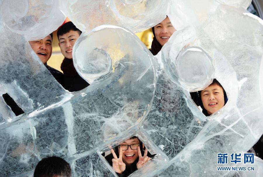 Des jeunes prennent la pose près d’une sculpture de glace dans la rue Zhongyang Dajie à Harbin, le 1er janvier 2015.