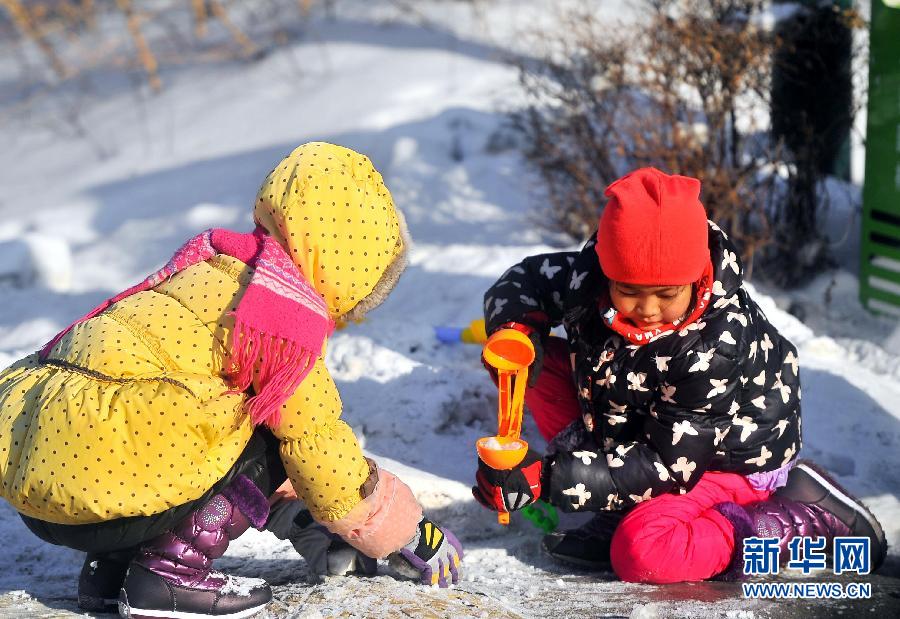 Deux enfants jouent dans la neige au Parc Nanhu à Changchun.