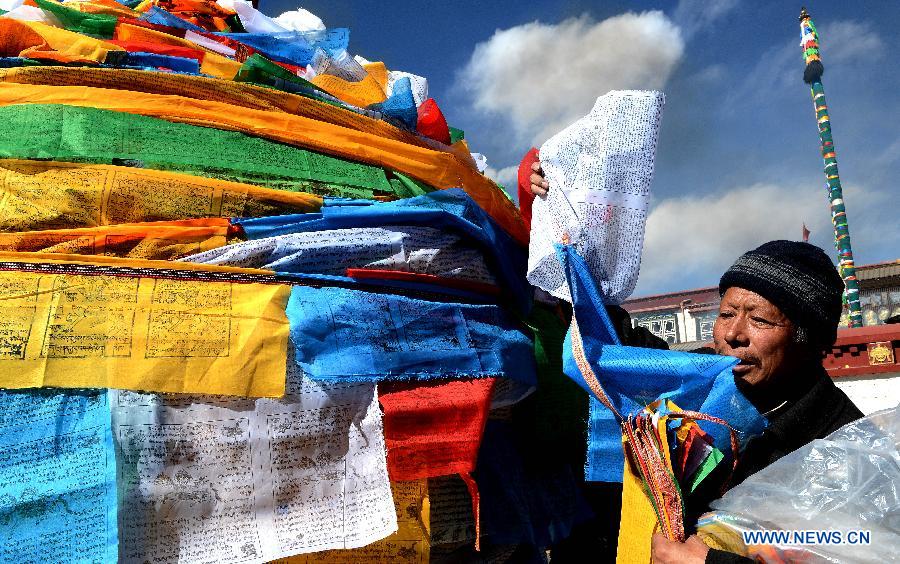 Un dévot fixe des drapeaux de prière sur un mât près du temple de Jokhang à Lhassa, capitale de la région autonome chinoise du Tibet (sud-ouest du pays), le 11 février 2015.
