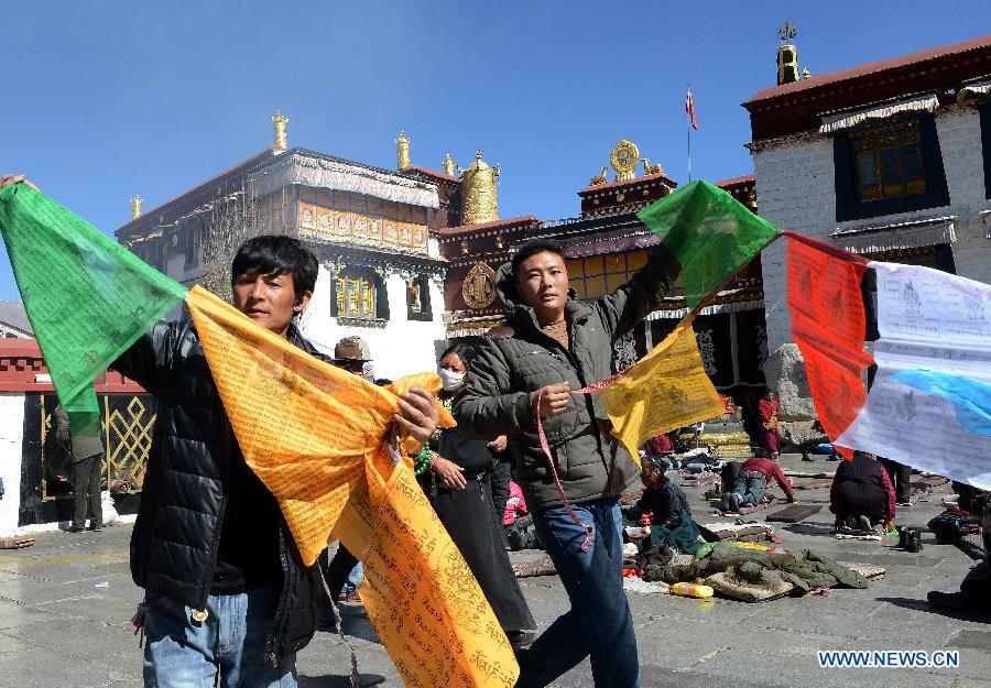 Des dévots tend des drapeaux de prière sur un poteau près du temple de Jokhang à Lhassa, capitale de la région autonome du Tibet dans le sud-ouest de la Chine, le 11 février 2015 .
