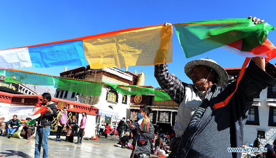 Des dévots tend des drapeaux de prière sur un poteau près du temple de Jokhang à Lhassa, capitale de la région autonome du Tibet dans le sud-ouest de la Chine, le 11 février 2015 .