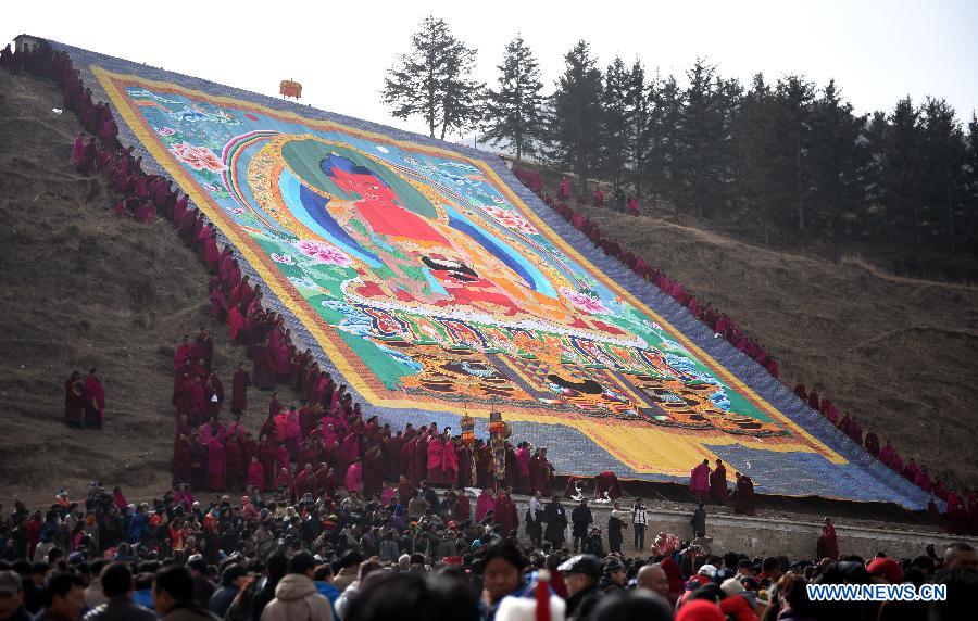 Plusieurs lamas et bouddhistes participent au rituel annuel de l'exposition d'une gigantesque thangka (peinture religieuse tibétaine) proche d'une colline pour le culte de disciples au monastère de Labrang à Xiahe, dans la province chinoise du Gansu (nord-ouest de la Chine), le 3 mars 2015. L'événement de la thangka, ou "l'exposition au soleil du Bouddha", lors des traditionnelles prières bouddhistes pour une bonne année. [Photo/Xinhua]