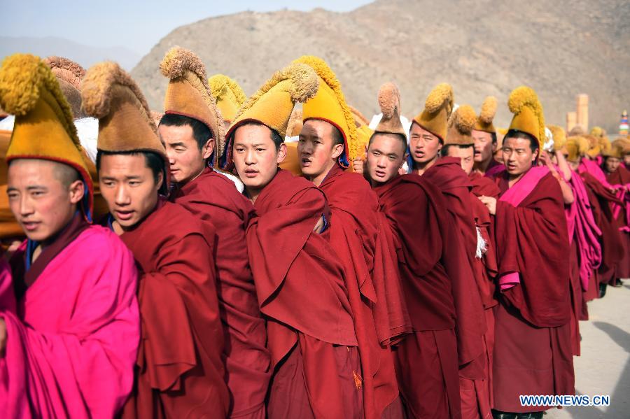 Des lamas portent sur l'épaule une immense thangka (peinture religieuse tibétaine) vers une colline pour le rituel annuel au monastère de Labrang à Xiahe, dans la province chinoise du Gansu (nord-ouest), le 3 mars 2015. [Photo/Xinhua]