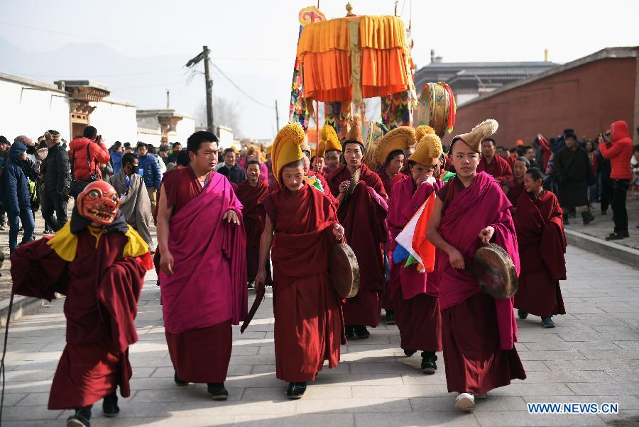 Des lamas portent sur l'épaule une immense thangka (peinture religieuse tibétaine) vers une colline pour le rituel annuel au monastère de Labrang à Xiahe, dans la province chinoise du Gansu (nord-ouest), le 3 mars 2015. [Photo/Xinhua]