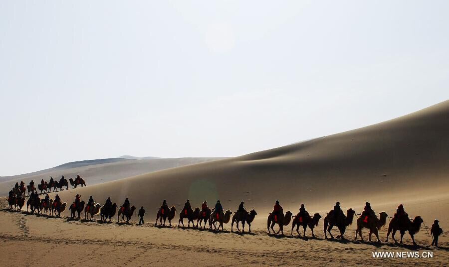 Des touristes visitent le site de la Source du Croissant de Lune à dos de chameau à Dunhuang, dans la Province du Gansu (Nord-ouest de la Chine). Avec le printemps, une certaine douceur revient, attirant les touristes. [Photo/Xinhua]