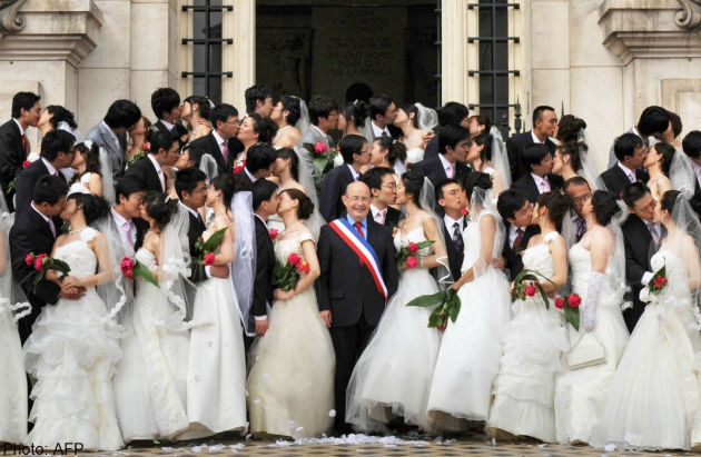 Photo d'archives de 2009 montrant Jean Germain entouré de 31 couples originaires de Tianjin.