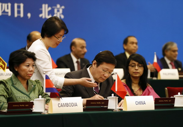 Le ministre chinois des Finances, Lou Jiwei, (au centre) paraphe un document, en présence de plusieurs invités lors de la cérémonie de signature de la Banque asiatique d'investissement pour les infrastructures. Evénement qui s'est déroulé au Grand Palais du Peuple à Beijing, le 24 octobre 2014. [Photo/Agences]
