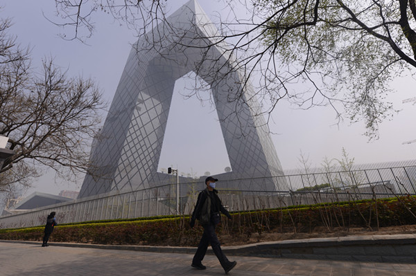 Un passant portant un masque, près du bâtiment de CCTV à Beijing, lors d'une journée brumeuse en avril dernier. [Photo/Wei Xiaochen/Asianewsphoto] 