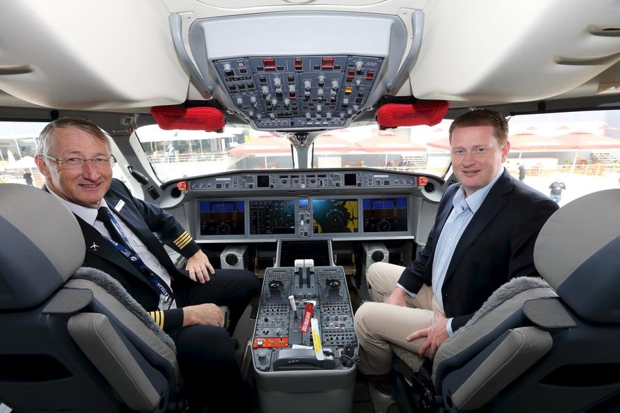 Ross Mitchell (à droite), vice-président de Bombardier Business Aquisition, pose avec le pilote Mark Elliott dans le cockpit de l'avion CS100. [Photo / Agences]
