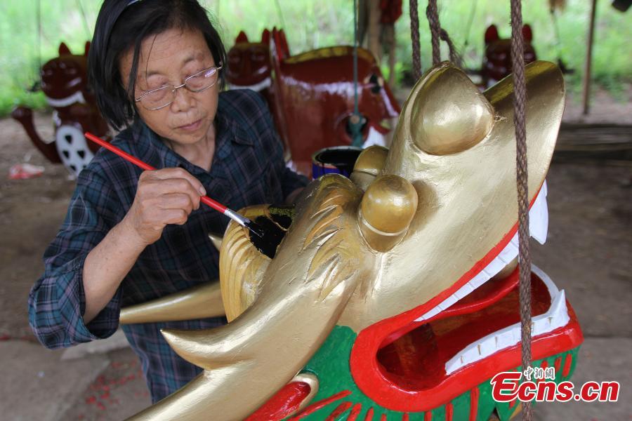 He Daizhen, la femme de Zhou Chengyun, peint une sculpture d'une tête de dragon qui sera utilisée dans une course de bateaux-dragons, dans le comté de Daoxian de la province du Hunan, en Chine centrale.