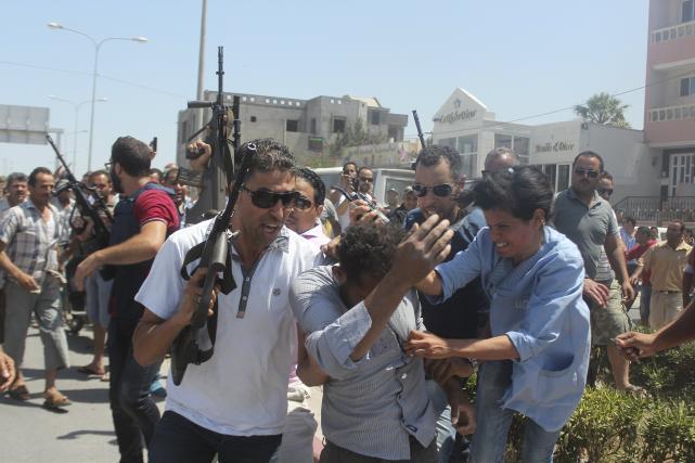 Des policiers tunisiens emmènent un homme suspecté d’avoir été impliqué dans l’attaque