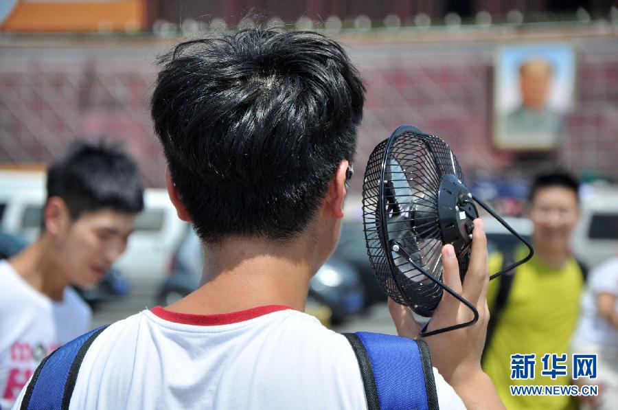 Un touriste sur la place Tian'anmen avec son mini ventilateur, le 13 juillet 2015.