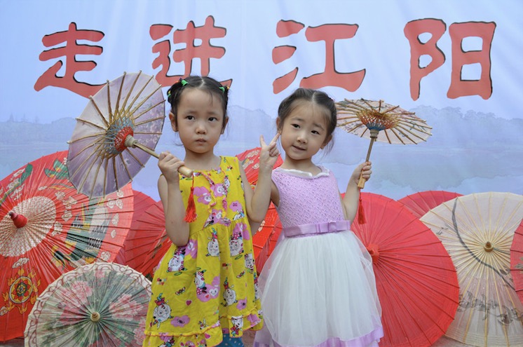 Deux fillettes tiennent un parapluie de papier d’huile pour prendre une photo.