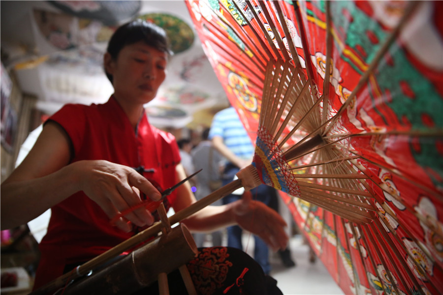 Une femme fabrique un parapluie de papier huilé dans le bourg de Fenshui, ville de Luzhou (province du Sichuan, Chine du Sud-Ouest), le 6 août 2015.