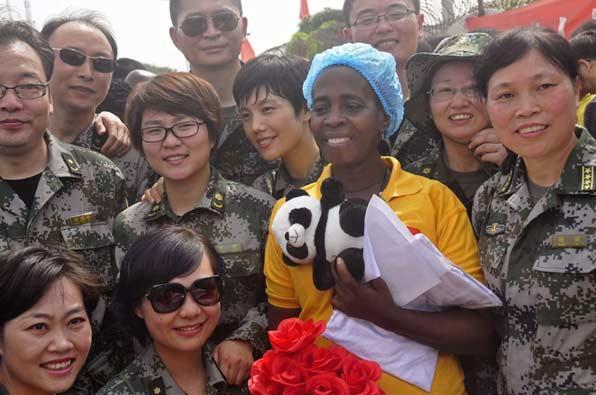 Beatrice Yardolo (au centre), une victime du virus Ebola, entourée par des travailleurs de la santé de l'armée chinoise, alors qu'elle quitte l'Unité de traitement d’Ebola dirigée par la Chine, où elle a reçu des soins à Monrovia, au Libéria, le 5 mars 2015. [Photo / IC]