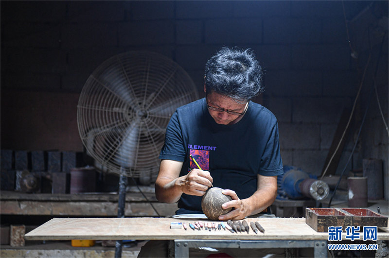 Un artisan gardant la sculpture de noix de coco millénaire