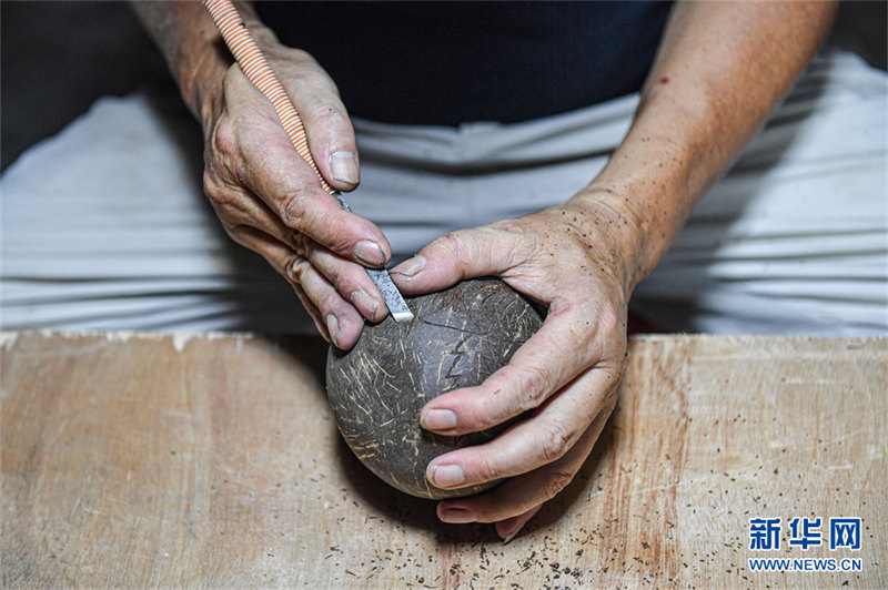 Un artisan gardant la sculpture de noix de coco millénaire