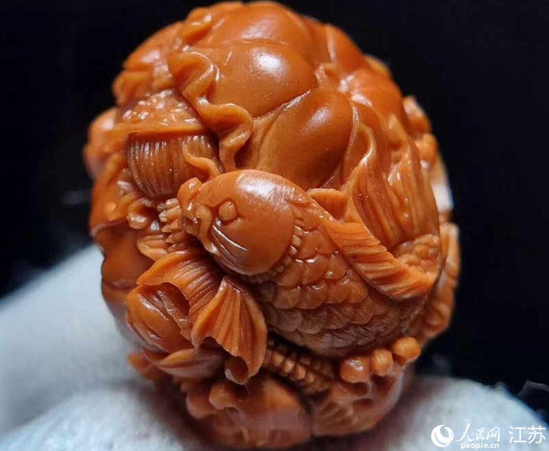 Photo montrant un travail de sculpture sur un noyau de fruits avec l'image d'un poisson, qui symbolise les souhaits d'abondance pour la nouvelle année. (Wang Jiliang / Le Quotidien du Peuple en ligne)