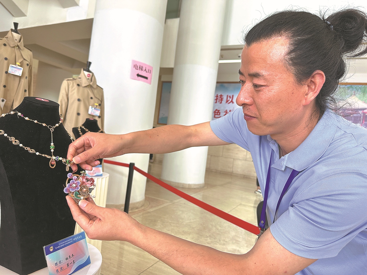 Du Dongdong arrange un collier qu'il a conçu pour le concours. (Zhao Ruixue / China Daily)