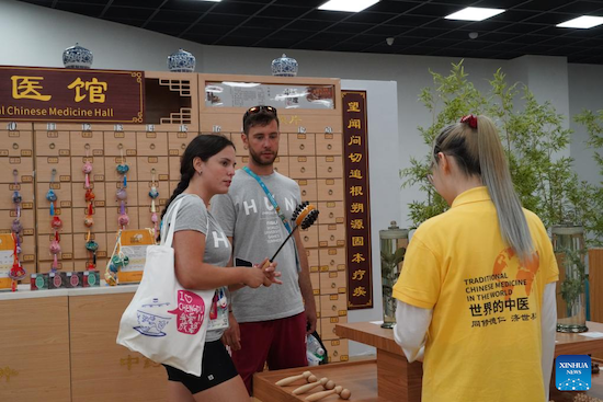 Anna Poltz, une athlète hongroise (à gauche) et sa coéquipière découvrent l'outil de soins de santé de la médecine traditionnelle chinoise (MTC) au village des Jeux de la FISU, également connus sous le nom d'Universiades, à Chengdu, capitale de la province du Sichuan (sud-ouest de la Chine), le 2 août 2023. (Tang Wenhao / Xinhua)