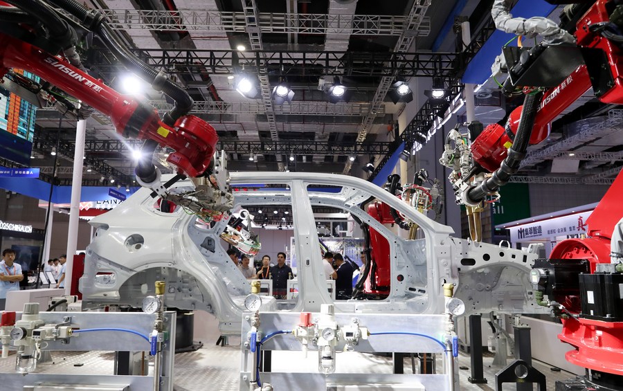 Des visiteurs observent un robot soudant une carrosserie automobile lors de la 23e édition du Salon international de l'industrie de Chine (CIIF), à Shanghai, dans l'est de la Chine, le 19 septembre 2023. (Photo : Fang Zhe)