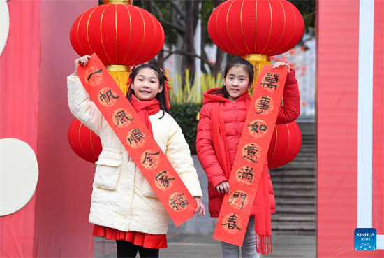 Deux filles montrent un couplet antithétique lors d'une activité d'écriture de couplets organisée pour la fête du Printemps. Cet événement a lieu dans le district de Yongchuan de la ville de Chongqing (sud-ouest de la Chine). (Photo / Xinhua)