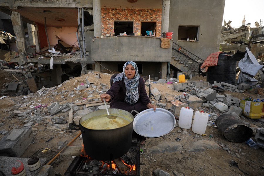 Une Palestinienne fait la cuisine au milieu des débris dans la ville de Khan Younis, dans le sud de la bande de Gaza, le 26 novembre 2023. (Xinhua/Yasser Qudih)