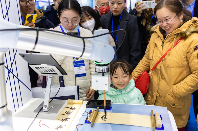 Des visiteurs regardent un robot intelligent écrire de la calligraphie lors de la Conférence mondiale de la fabrication intelligente 2023 à Nanjing, capitale de la province du Jiangsu (est de la Chine), le 6 décembre 2023. (Photo / Xinhua)