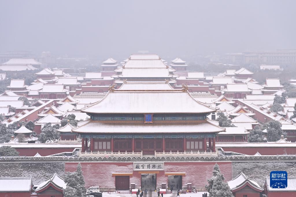 Le 11 décembre, des passants prennent des photos de la neige près d'une des tours d'angle de la Cité interdite. (Li Xin / Xinhua)