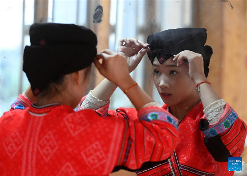 Une femme s'habille avec un costume traditionnel des Hongyao. (Lu Boan / Xinhua)