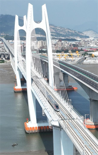 Photo aérienne prise le 19 septembre 2023 montrant un train à grande vitesse Fuxing circulant sur le pont maritime de la baie d'Anhai (à gauche), le long de la ligne à grande vitesse Fuzhou-Xiamen-Zhangzhou, dans la province du Fujian (sud-est de la Chine). (Lin Shanchuan / Xinhua)